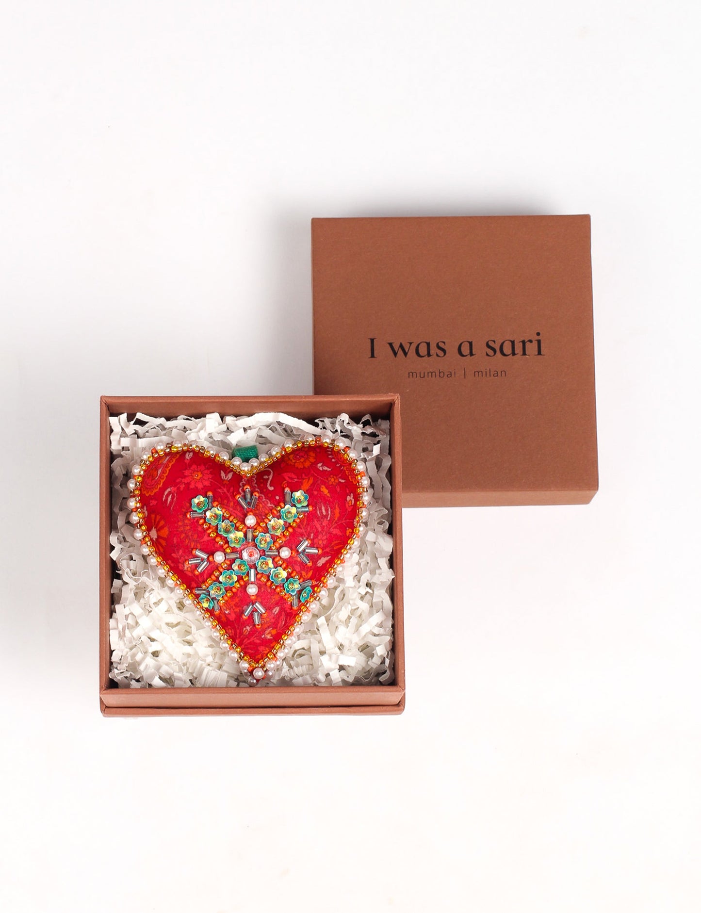 A Christmas heart ornament made from recycled sari fabric, featuring traditional Aari embroidery, representing sustainable, eco-friendly fashion. Handcrafted by artisans, this zero-waste, fair trade product symbolizes recycled material clothing and conscious clothing choices within eco-friendly and circular fashion.