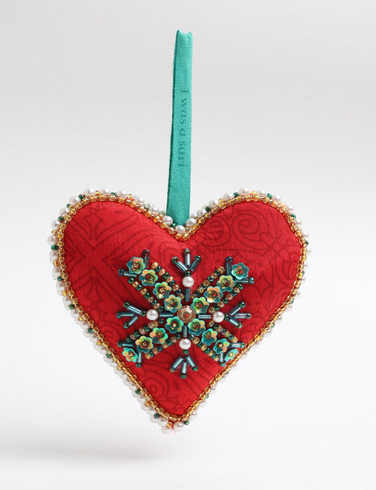 A Christmas heart ornament made from recycled sari fabric, featuring traditional Aari embroidery, representing sustainable, eco-friendly fashion. Handcrafted by artisans, this zero-waste, fair trade product symbolizes recycled material clothing and conscious clothing choices within eco-friendly and circular fashion.
