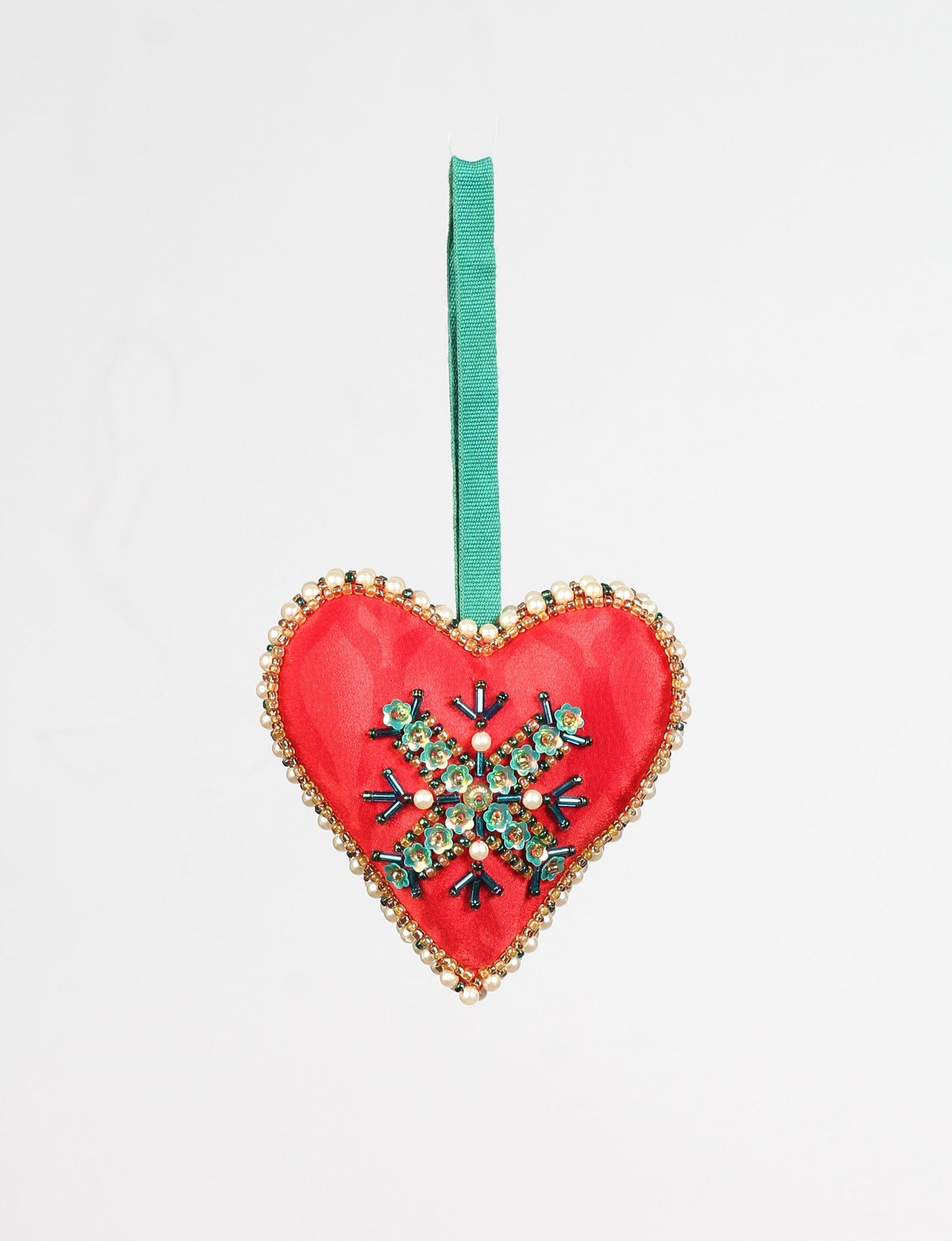 A Christmas heart ornament made from recycled sari fabric, featuring traditional Aari embroidery, representing sustainable, eco-friendly fashion. Handcrafted by artisans, this zero-waste, fair trade product symbolizes recycled material clothing and conscious clothing choices within eco-friendly and circular fashion.