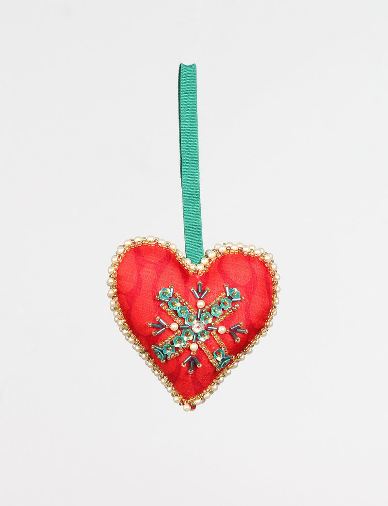 Red heart-shaped ornament with green floral bead design, pearl and gold bead trim, hanging from a green ribbon loop