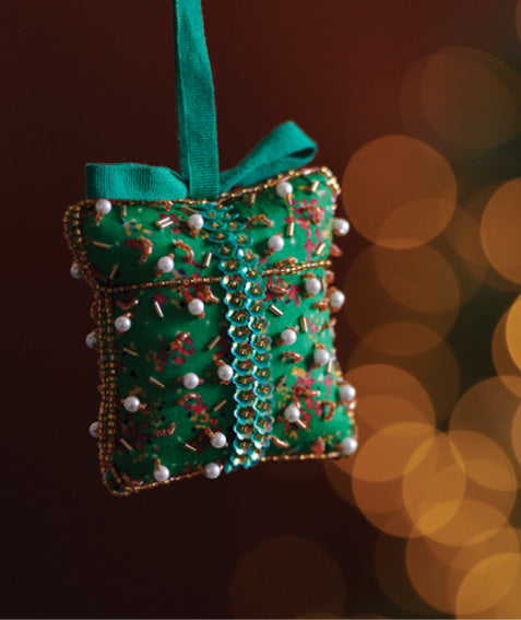 Green fabric gift ornament with gold and red embroidery, white bead accents, and a green hanging ribbon