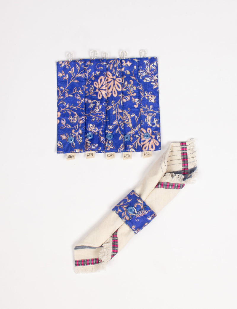 Set of six blue fabric napkin rings with beige floral print and blue buttons, shown flat and one wrapped around a beige napkin
