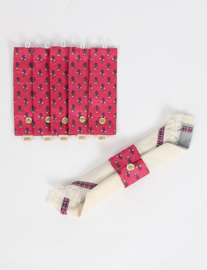 Set of six pink floral fabric napkin rings with button closures and "I was a sari" tags, shown flat and on a rolled napkin
