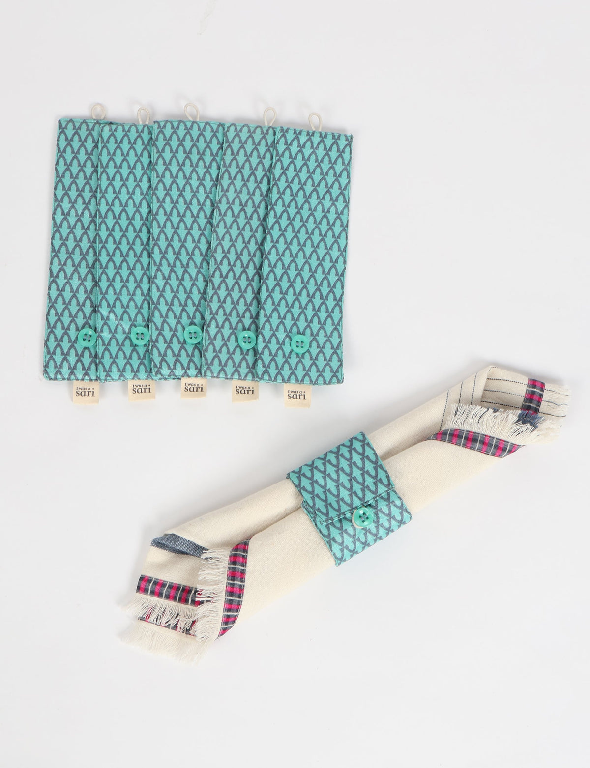 Set of five blue fabric napkin rings with micro pattern and button closure, one wrapped around a cream napkin with plaid border