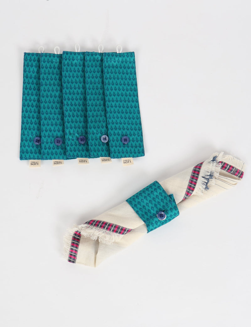 Set of six blue fabric napkin rings with micro teardrop pattern and button closure, one holding a rolled napkin with plaid trim