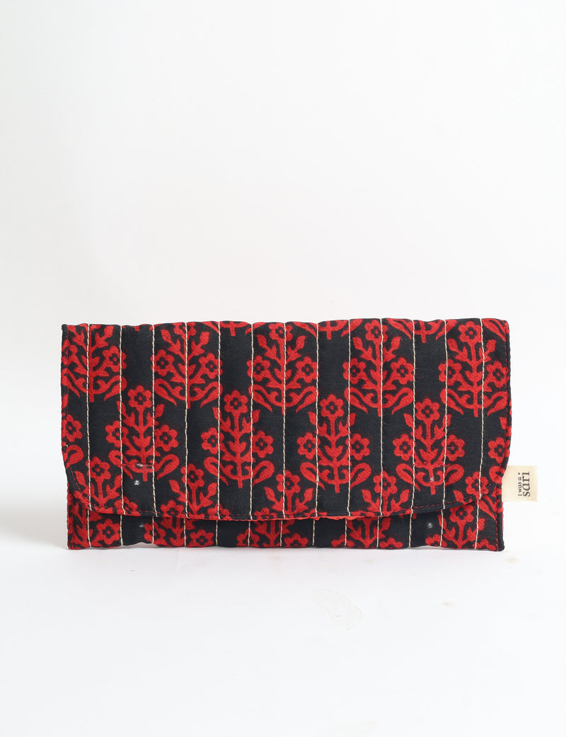Black quilted sunglasses case with red tropical floral pattern and visible beige brand tag on side, front view