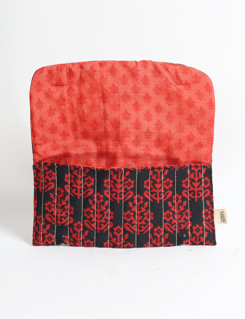 Quilted sunglasses case with black and red floral pattern exterior and red tropical print interior, open flat on white