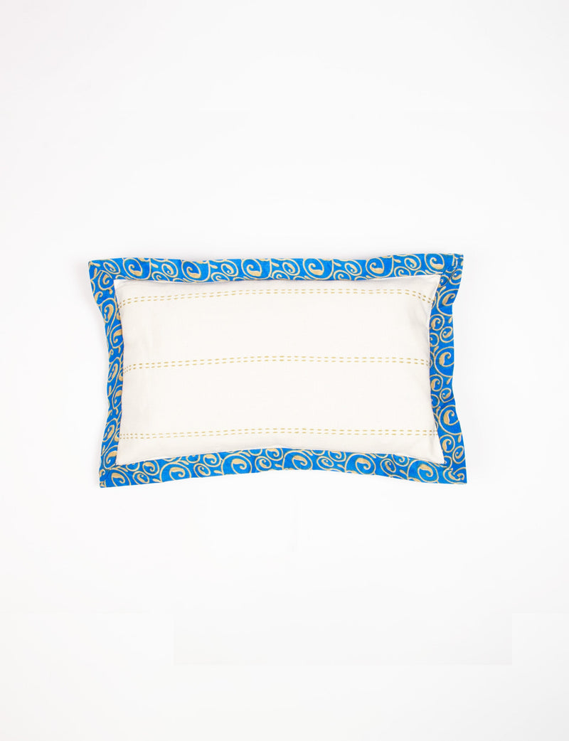 Rectangular lumbar cotton cushion cover with cream center and broad blue sari edging with gold swirl pattern, flat lay view