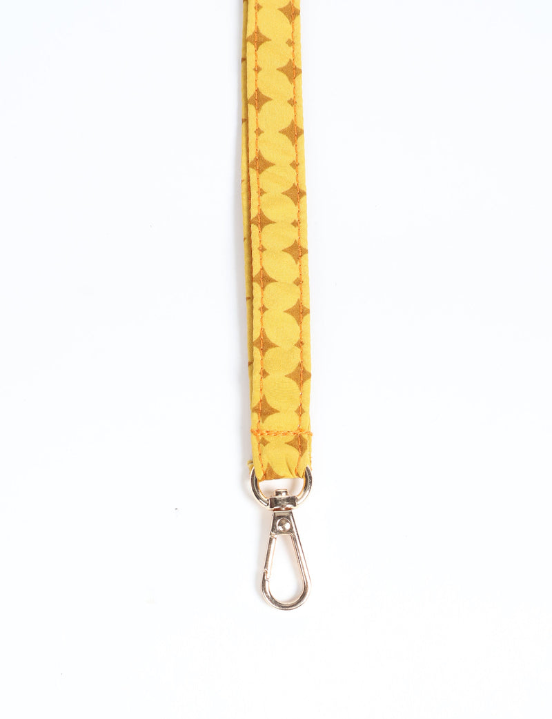 Yellow fabric keychain lanyard with brown geometric pattern and silver metal clasp, shown flat on white background