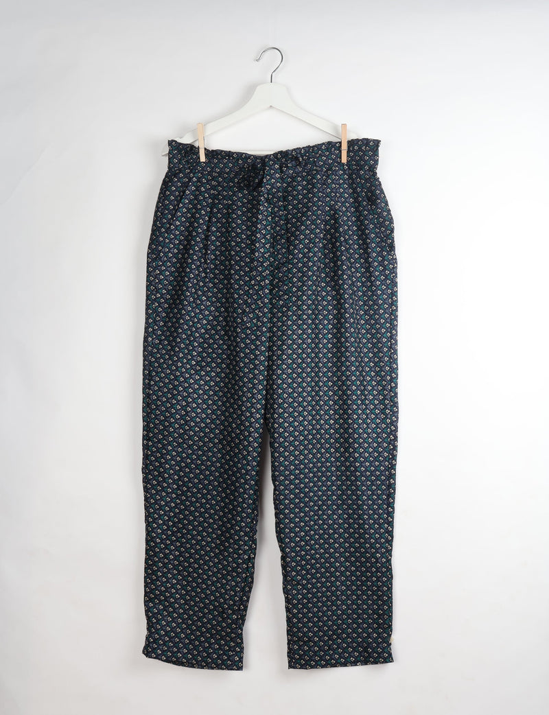 Blue paperbag high-waisted pull-on pants with a small geometric pattern, hanging on a white hanger against a white background