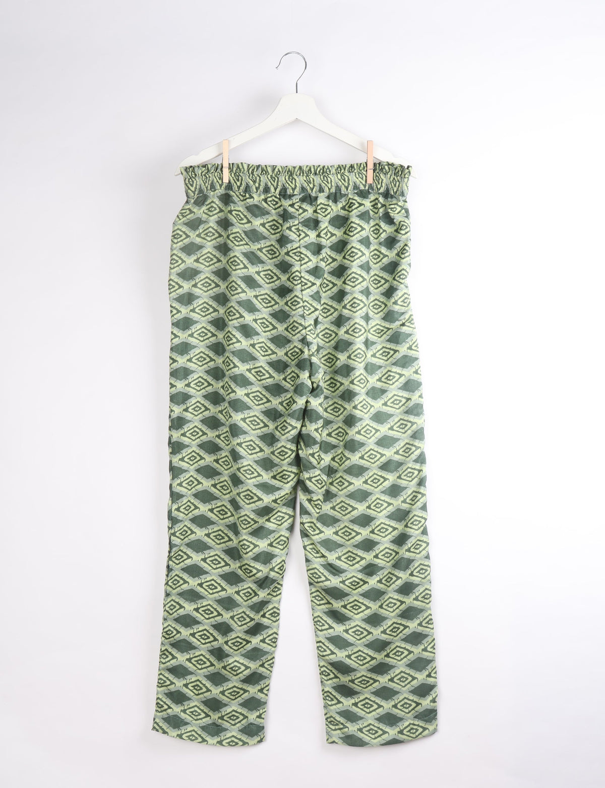 Green geometric patterned paperbag high-waisted pull-on pants hanging on white hanger, front view