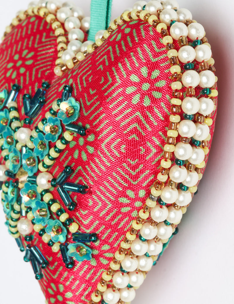 Red fabric heart ornament with yellow and pink floral print, decorated with pearl beads and blue flower-shaped sequins
