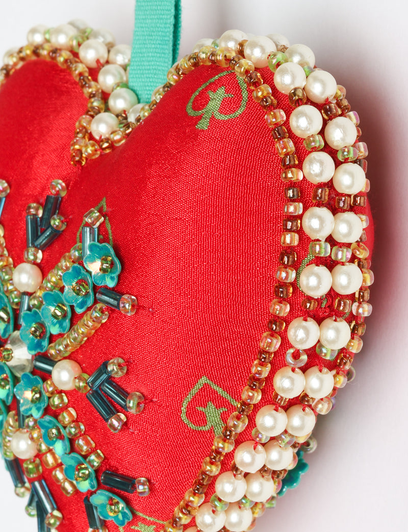 Red fabric heart ornament with yellow and pink floral print, decorated with pearl beads and blue flower-shaped sequins
