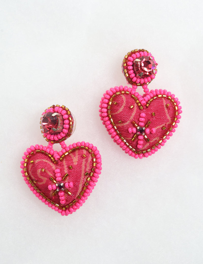 Pink heart drop earrings with fabric centers, pink and gold bead trim, and red rhinestone accents, shown on white background