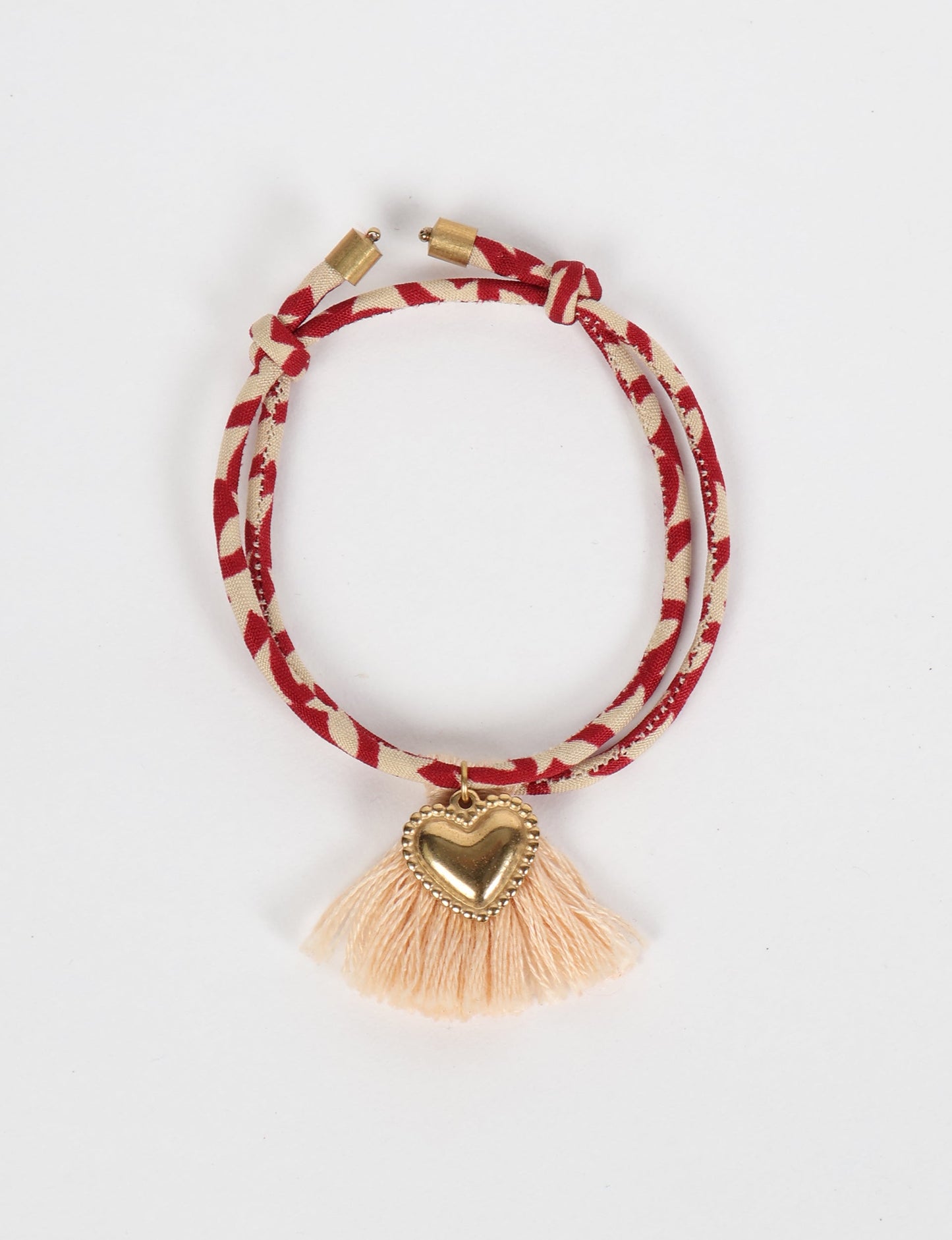 Handmade rope bracelet from recycled sari fabric with gold heart charm and tassels—eco friendly cloth, climate neutral fashion, and upcycled women’s clothing.