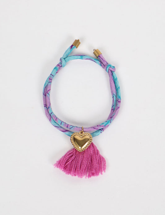 Handmade rope bracelet from recycled sari fabric with gold heart charm and tassels—eco friendly cloth, climate neutral fashion, and upcycled women’s clothing.