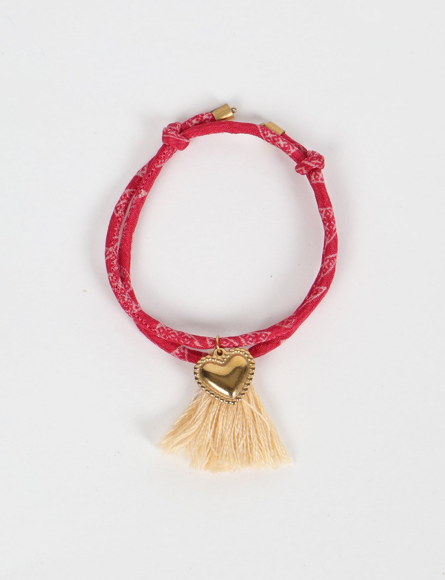 Handmade rope bracelet from recycled sari fabric with gold heart charm and tassels—eco friendly cloth, climate neutral fashion, and upcycled women’s clothing.