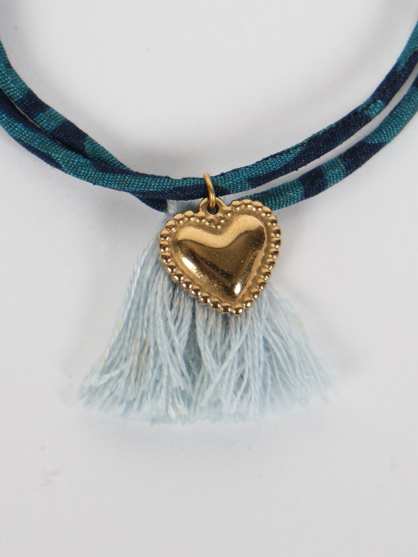 Handmade rope bracelet from recycled sari fabric with gold heart charm and tassels—eco friendly cloth, climate neutral fashion, and upcycled women’s clothing.