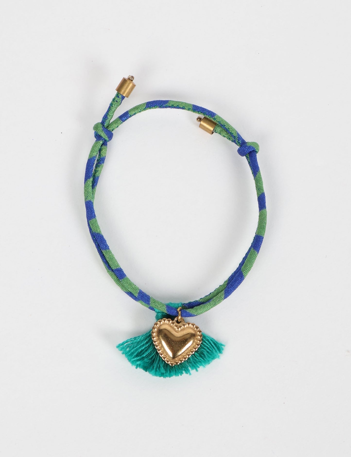 Handmade rope bracelet from recycled sari fabric with gold heart charm and tassels—eco friendly cloth, climate neutral fashion, and upcycled women’s clothing.