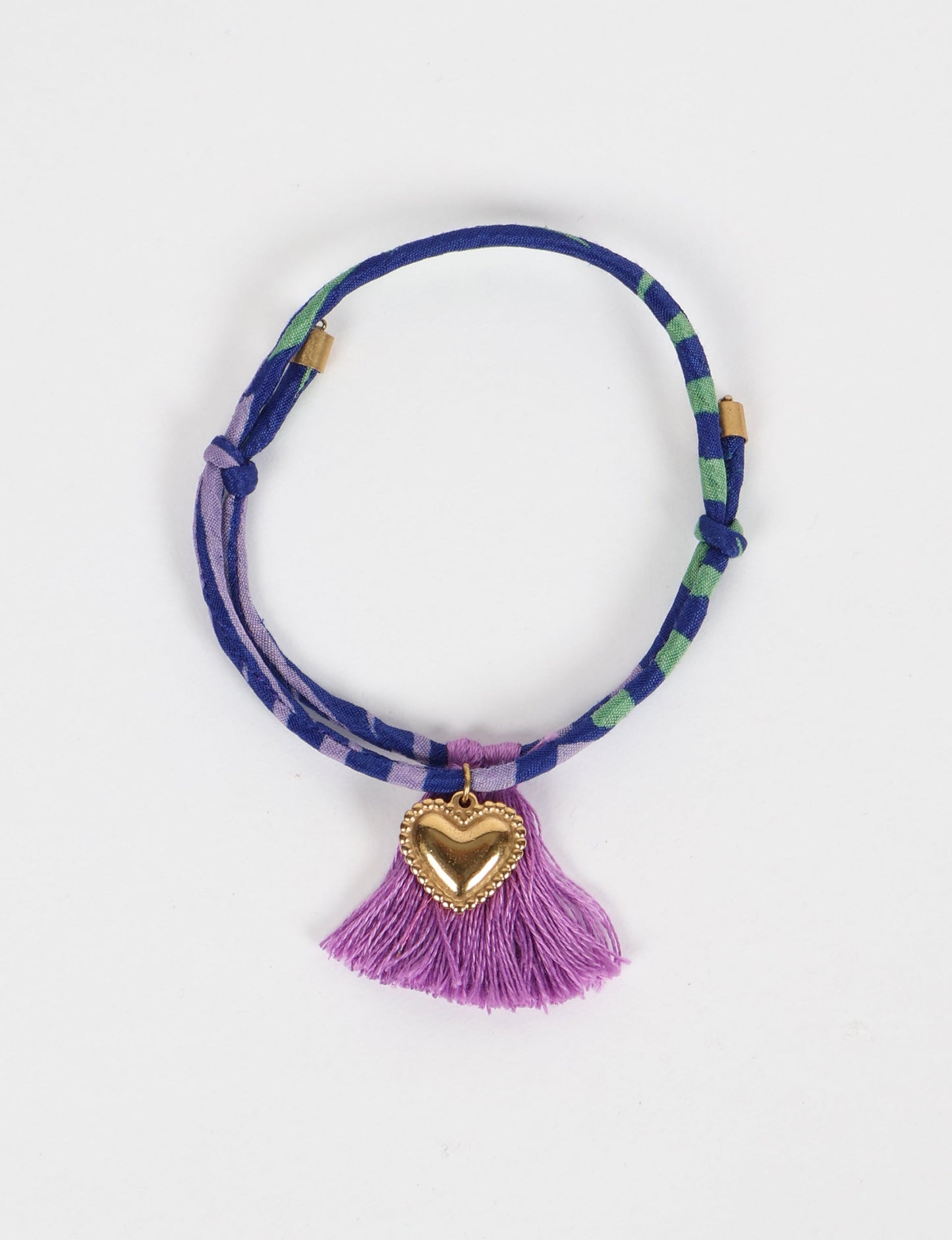 Handmade rope bracelet from recycled sari fabric with gold heart charm and tassels—eco friendly cloth, climate neutral fashion, and upcycled women’s clothing.