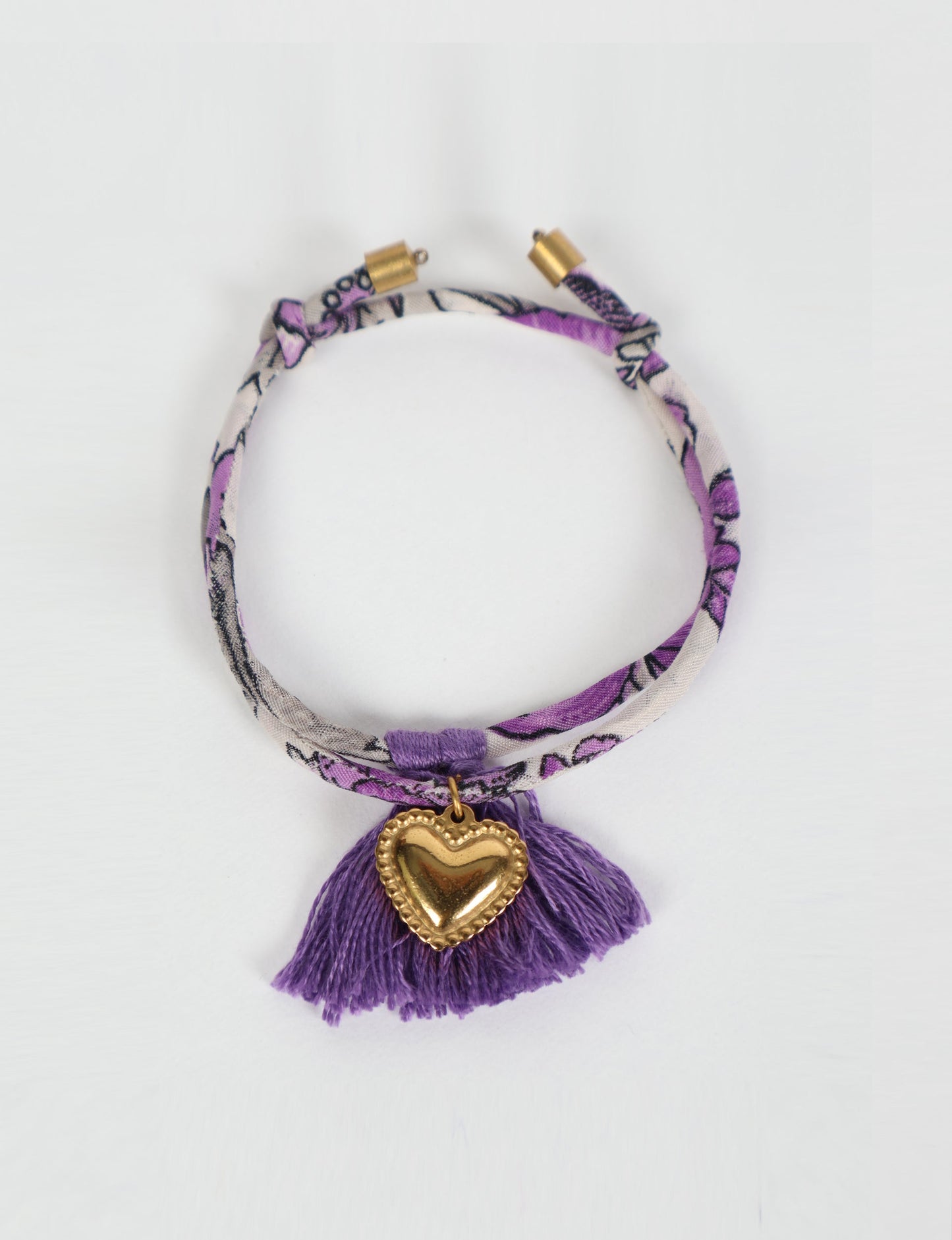 Handmade rope bracelet from recycled sari fabric with gold heart charm and tassels—eco friendly cloth, climate neutral fashion, and upcycled women’s clothing.