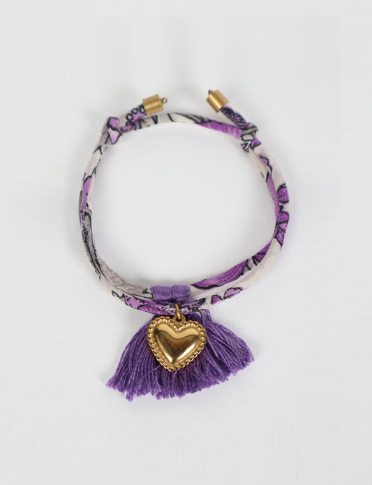 Handmade rope bracelet from recycled sari fabric with gold heart charm and tassels—eco friendly cloth, climate neutral fashion, and upcycled women’s clothing.