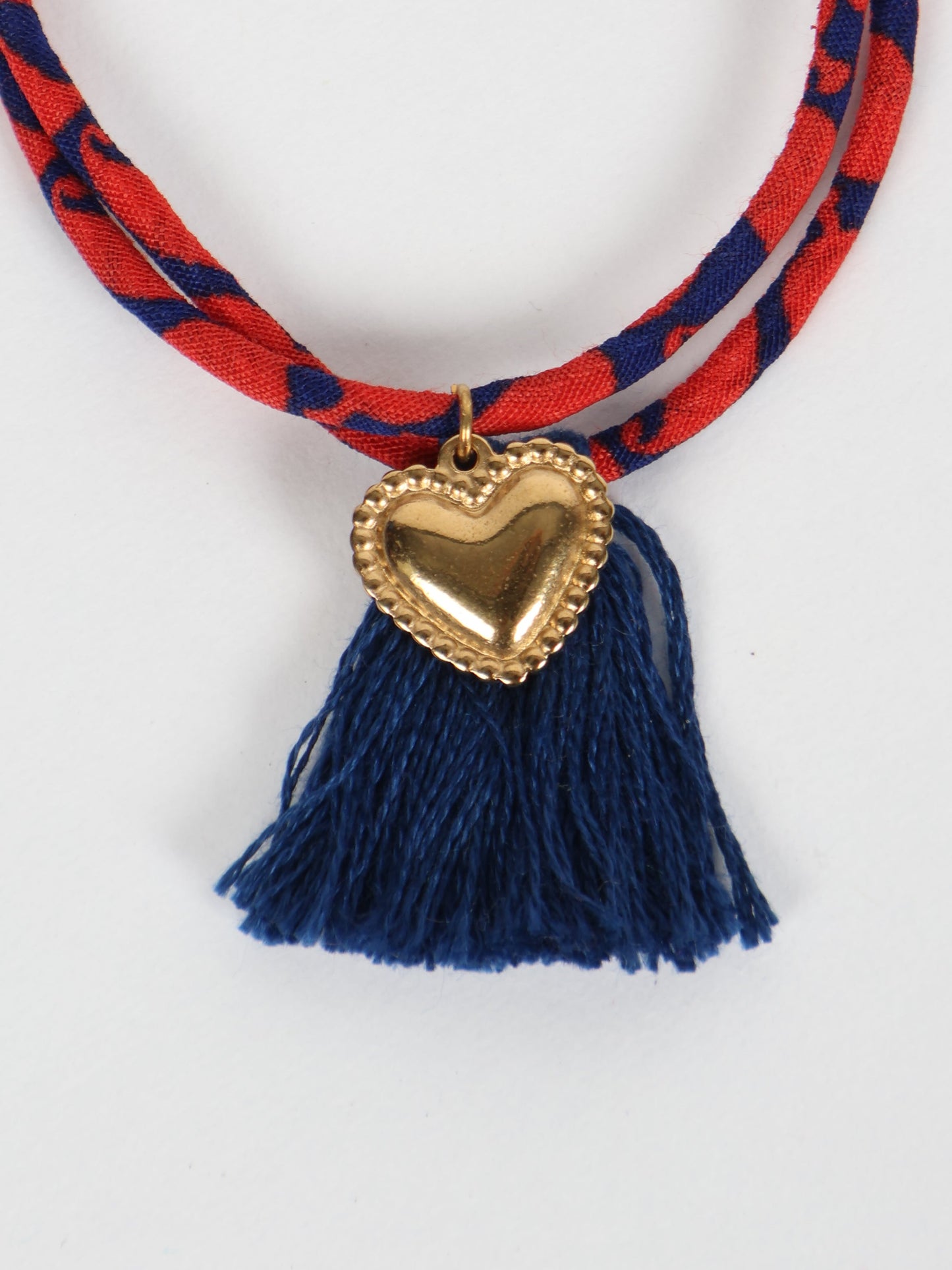 Handmade rope bracelet from recycled sari fabric with gold heart charm and tassels—eco friendly cloth, climate neutral fashion, and upcycled women’s clothing.