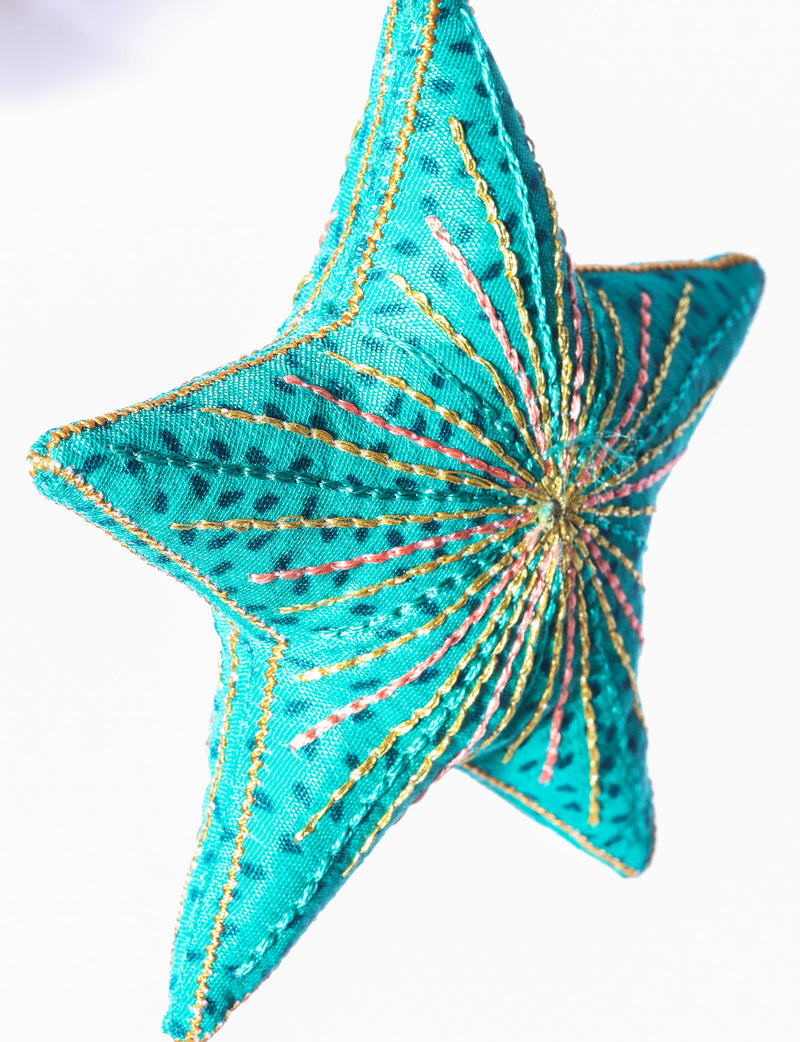 Timeless star ornament made from recycled sari fabric, featuring silk and metallic embroidery, crafted as part of green fashion, recycled clothing design, environmentally friendly clothing practices, and repurposed clothing traditions.
