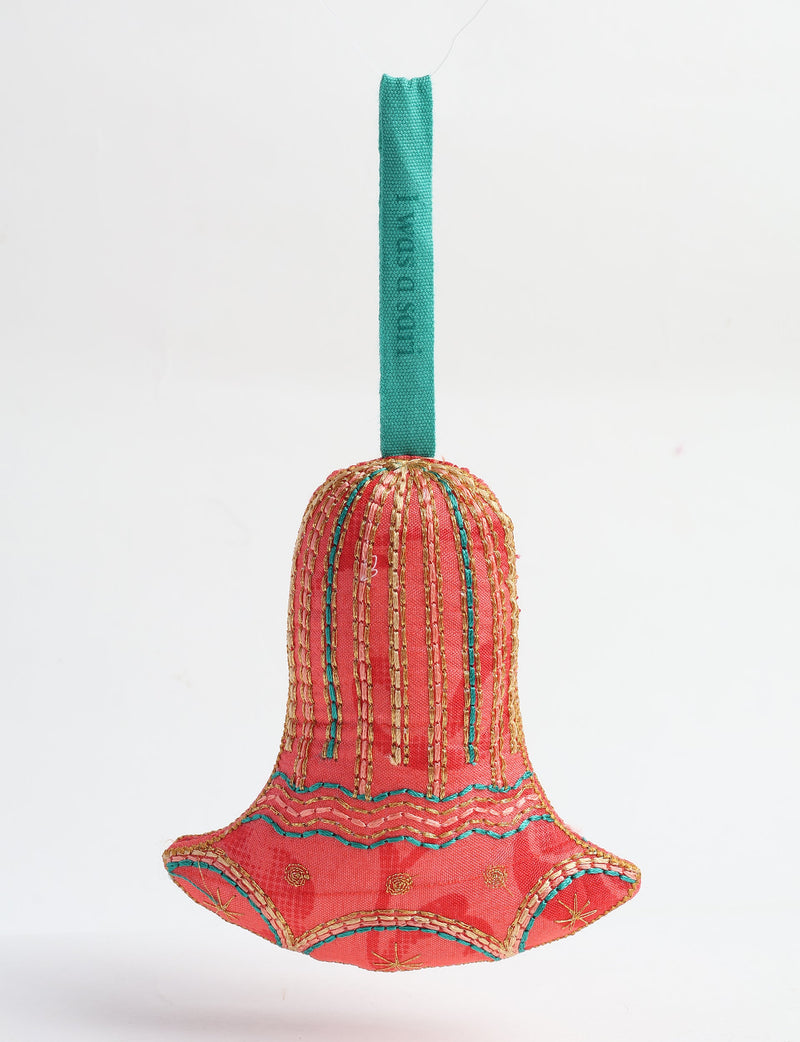 Red fabric bell ornament with gold and teal stitched patterns and a teal hanging loop with faint text