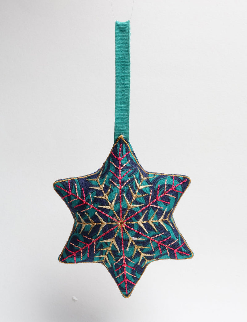 Blue fabric star ornament with embroidered gold and pink snowflake design and teal hanging loop, front view on white background