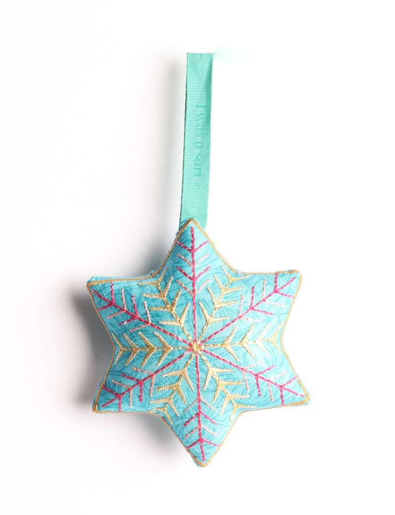Blue fabric star-shaped ornament with gold and pink embroidered snowflake design and green hanging loop