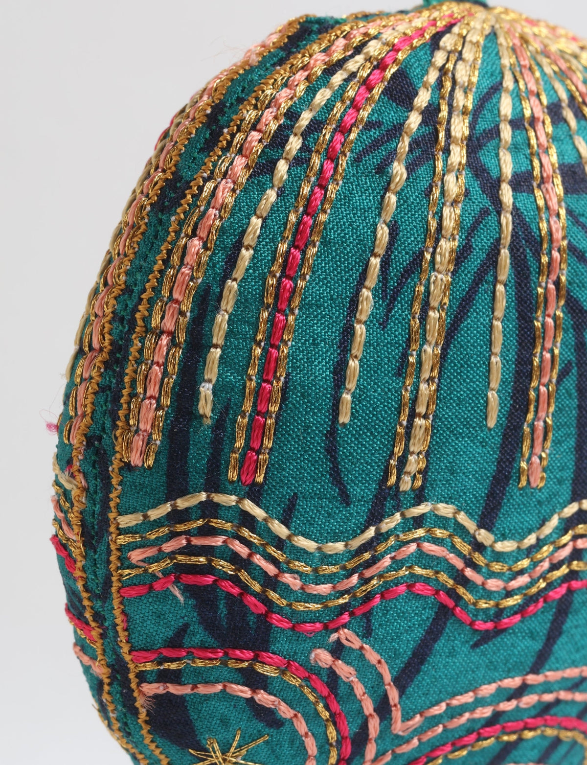 Green fabric full moon ornament with abstract dark blue print and multicolored gold, pink, and beige embroidery details