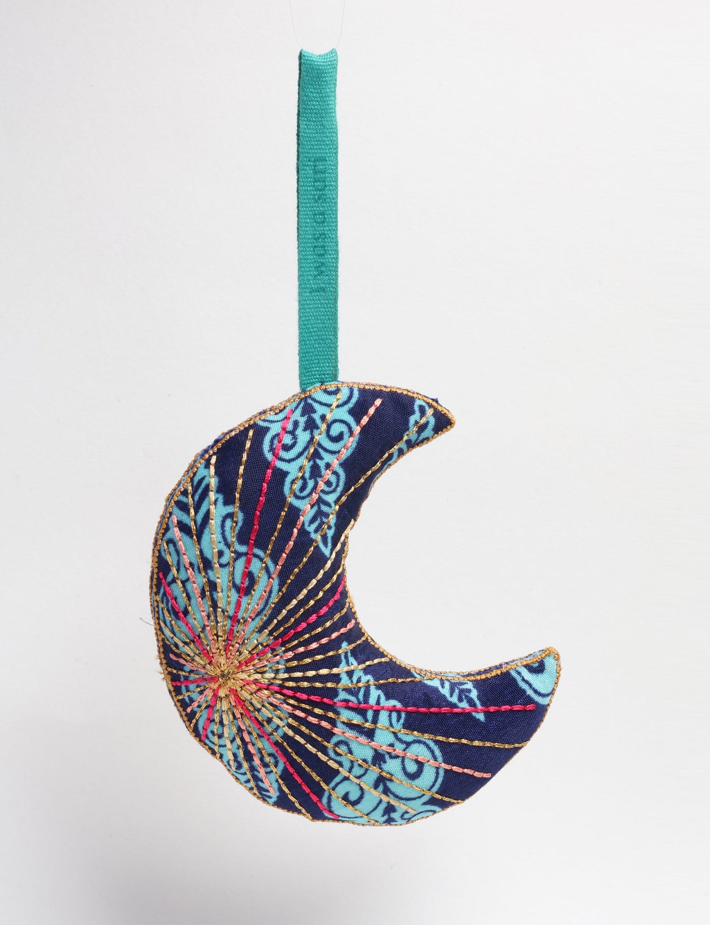 Timeless crescent moon ornament made from recycled materials and textile waste, featuring intricate embroidery. A zero waste and carbon offset accessory that supports circular fashion, fair trade fashion, and environmentally friendly clothing choices.