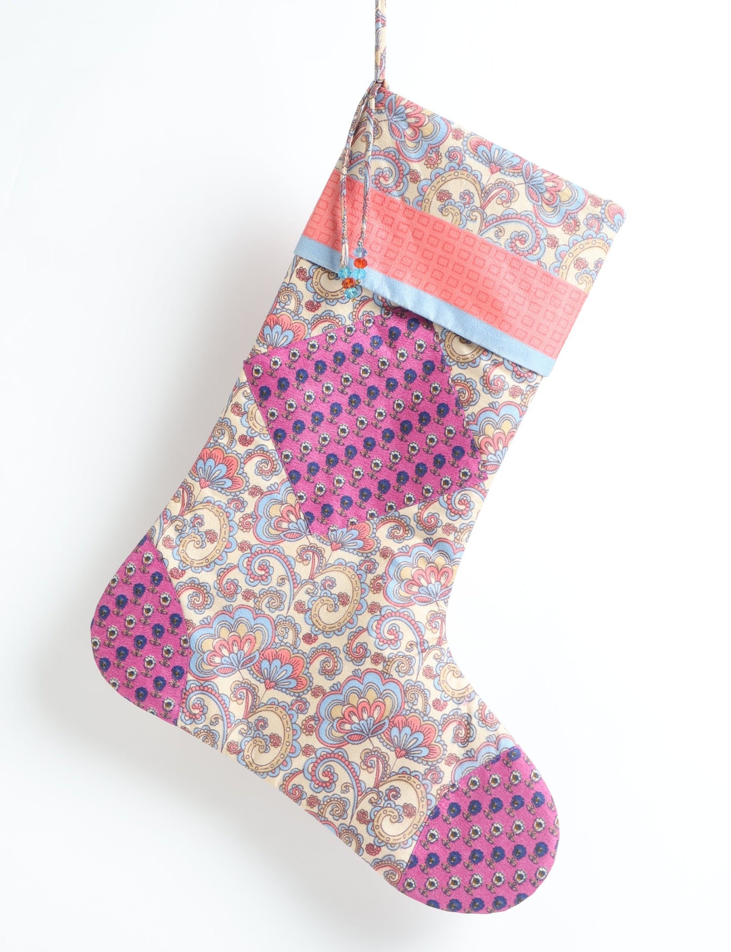 Timeless Christmas stocking made from recycled sari fabric, featuring colorful patchwork, tassel details, and crafted with care in line with circular fashion, upcycling fashion, carbon neutral clothing, and environmentally friendly clothing ideals — a beautiful piece of repurposed clothing and eco clothing for sustainable women’s fashion.