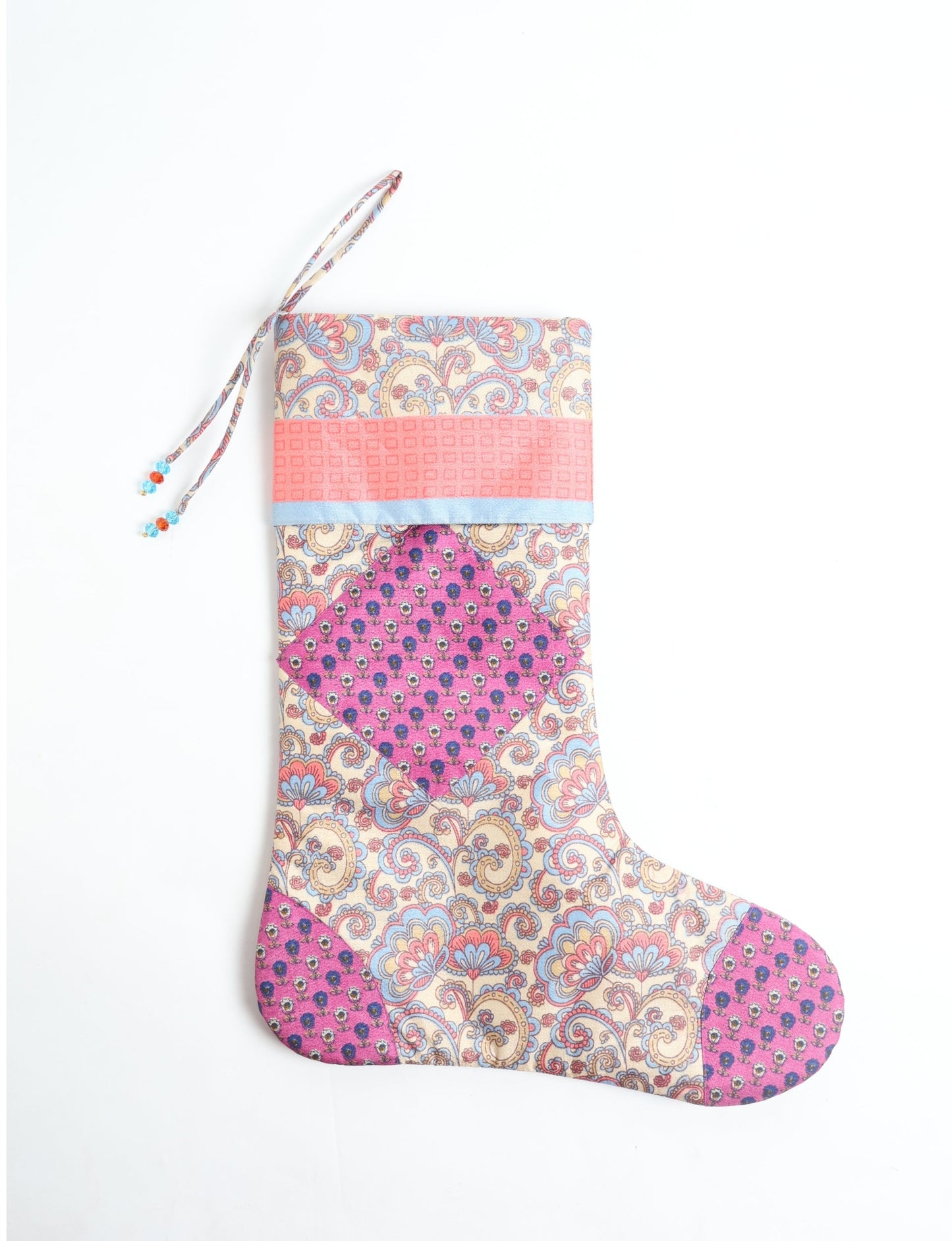 Timeless Christmas stocking made from recycled sari fabric, featuring colorful patchwork, tassel details, and crafted with care in line with circular fashion, upcycling fashion, carbon neutral clothing, and environmentally friendly clothing ideals — a beautiful piece of repurposed clothing and eco clothing for sustainable women’s fashion.
