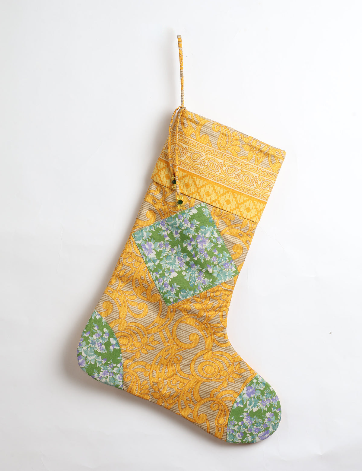 Timeless Christmas stocking made from recycled sari fabric, featuring colorful patchwork, tassel details, and crafted with care in line with circular fashion, upcycling fashion, carbon neutral clothing, and environmentally friendly clothing ideals — a beautiful piece of repurposed clothing and eco clothing for sustainable women’s fashion.