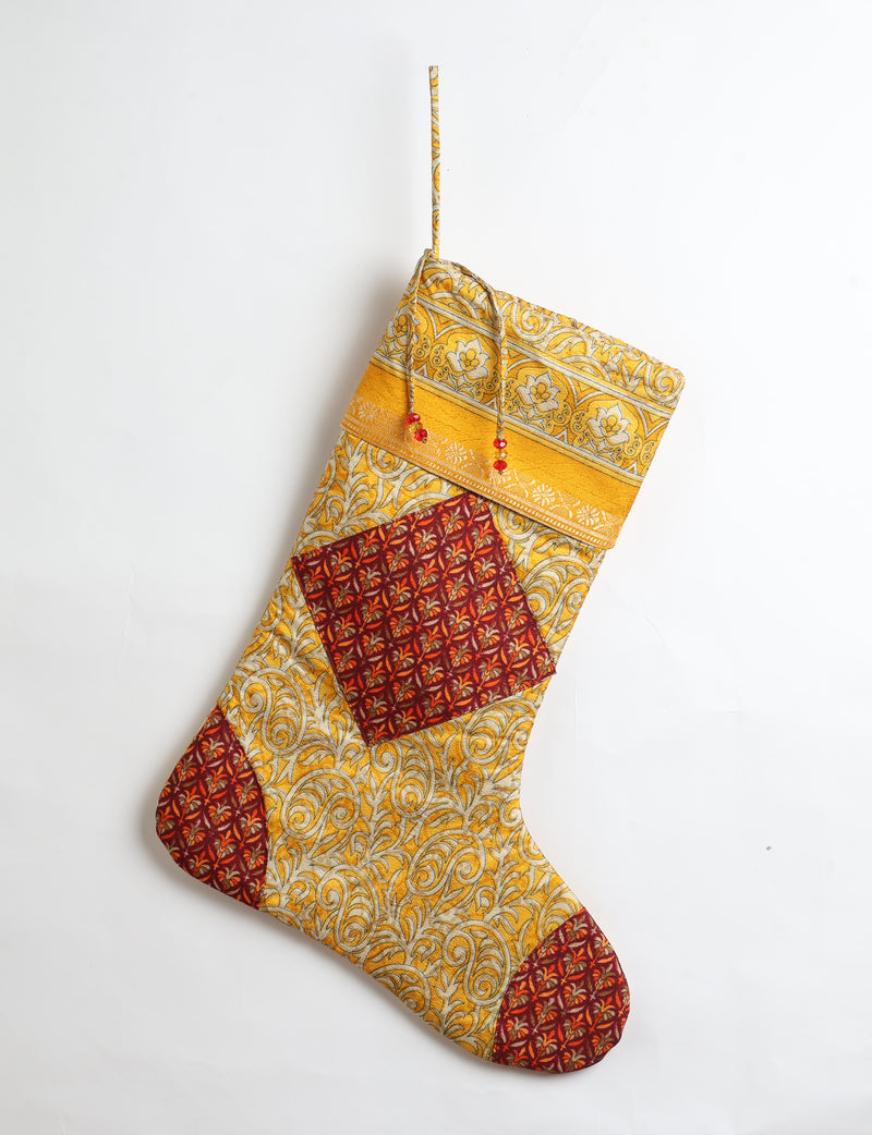 Timeless Christmas stocking made from recycled sari fabric, featuring colorful patchwork, tassel details, and crafted with care in line with circular fashion, upcycling fashion, carbon neutral clothing, and environmentally friendly clothing ideals — a beautiful piece of repurposed clothing and eco clothing for sustainable women’s fashion.