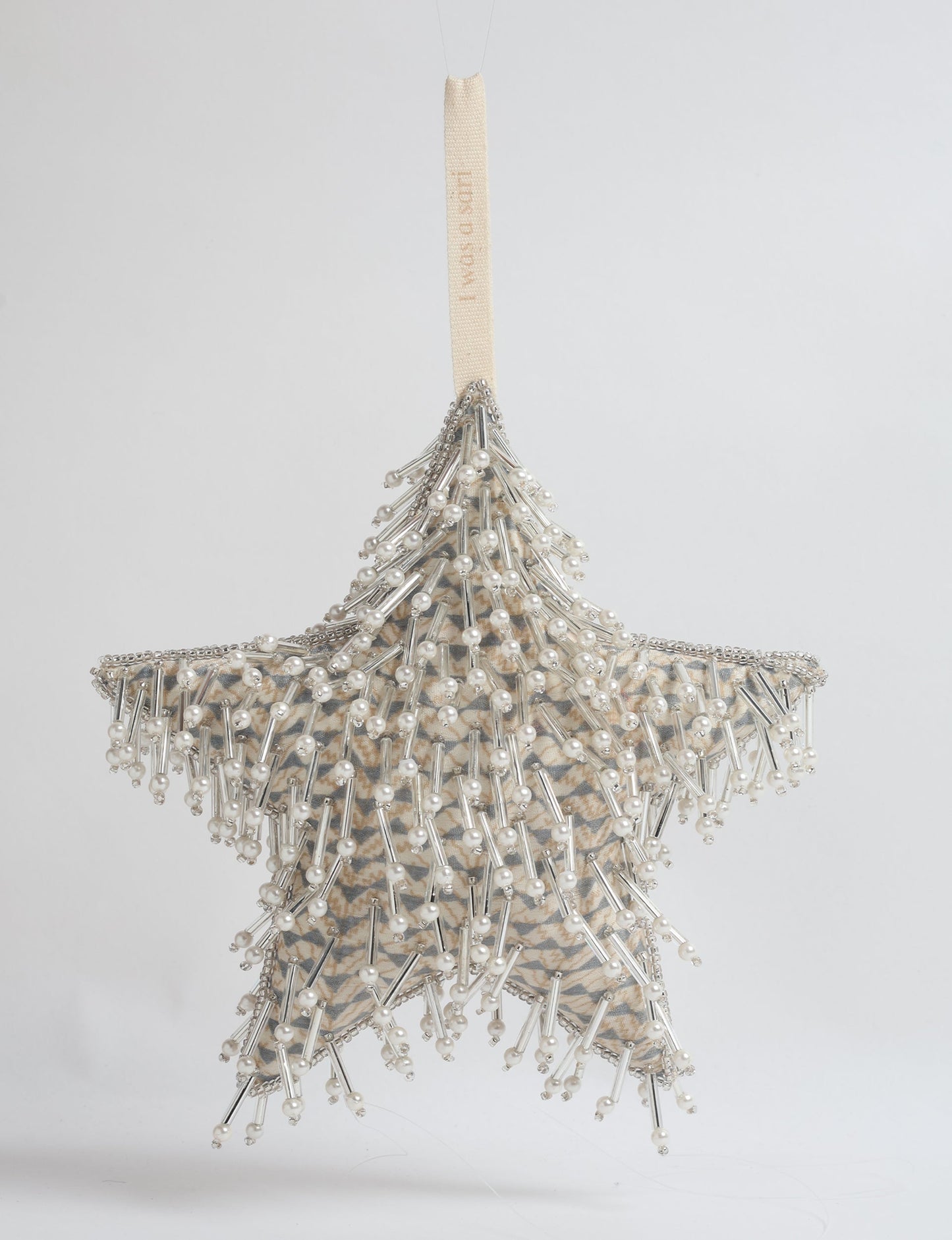 Beige star ornament with micro pattern, decorated with silver beads and pearls, hanging by a beige fabric loop
