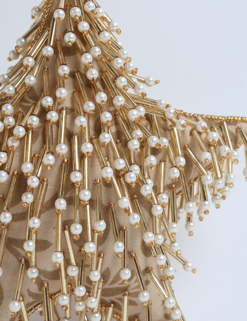 Beige fabric star ornament decorated with gold tubes and white pearl beads in a close-up view
