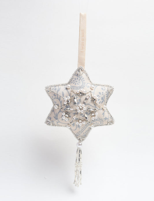 Silver snowflake ornament made from ivory and grey recycled sari products, enhanced with silver beads and pearls. Designed for lovers of eco friendly products, climate neutral clothing, and repurposed clothing, supporting zero waste clothing and conscious clothing movements.