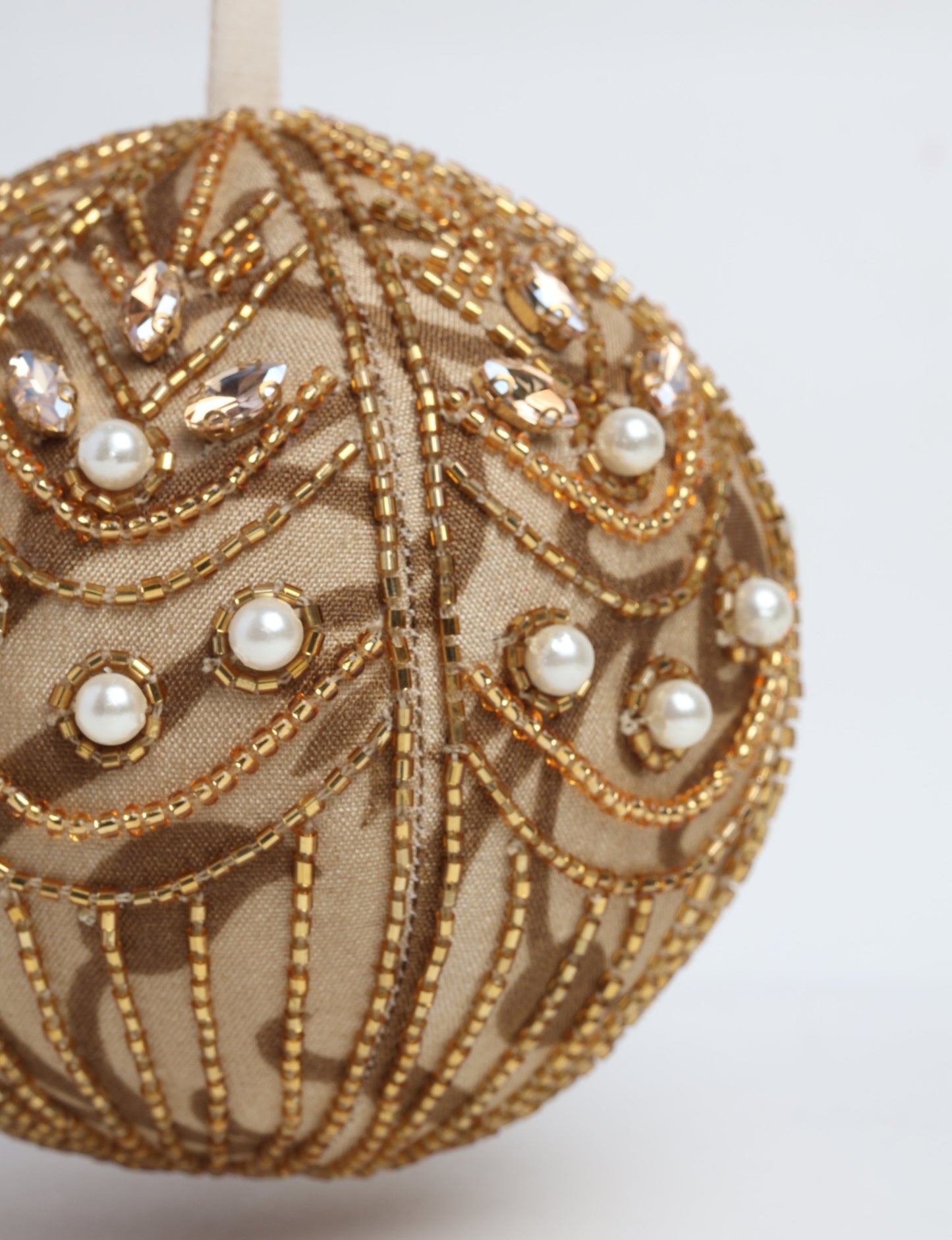 Gold colored ball ornament handcrafted from recycled sari products and repurposed clothing, featuring silver hand embroidery, pearls, sequins, and beads. Made through circular fashion and sustainable women’s clothing processes, this piece represents eco friendly fashion, carbon neutral clothing, and environmentally friendly clothing inspired by conscious clothing principles.