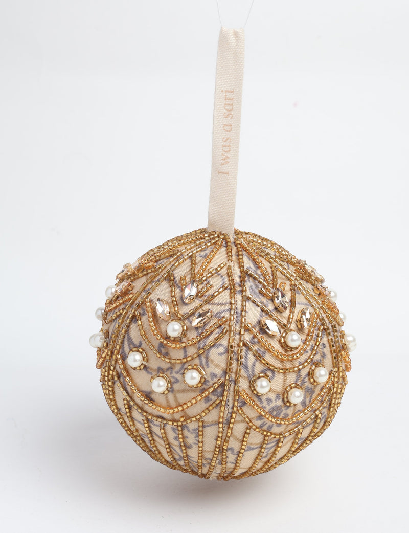 Gold fabric ball ornament decorated with gold beads, pearls, and clear rhinestones, hanging by a cream ribbon with text