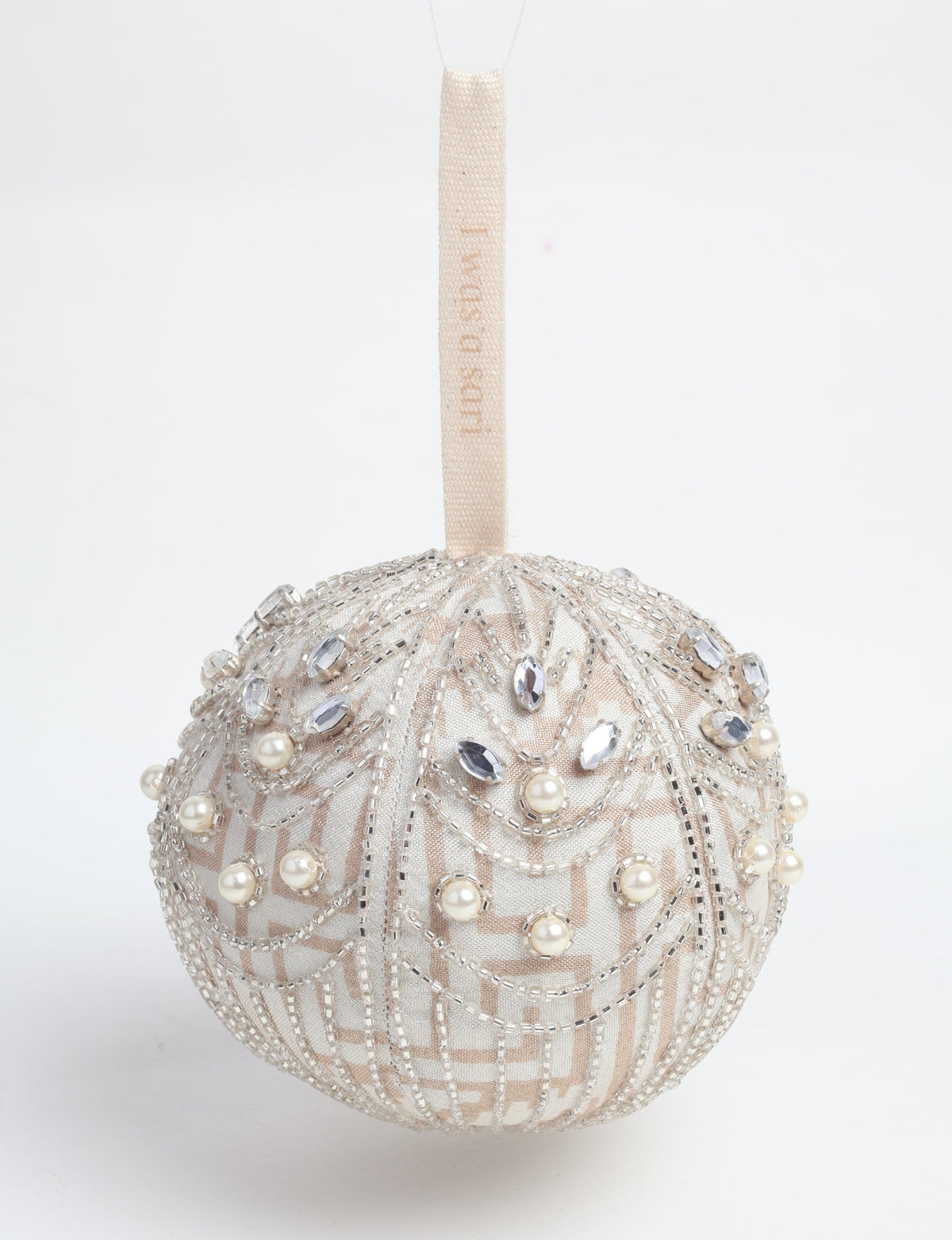 Silver ball ornament with pearl and crystal bead embellishments and a beige hanging loop with faint text visible