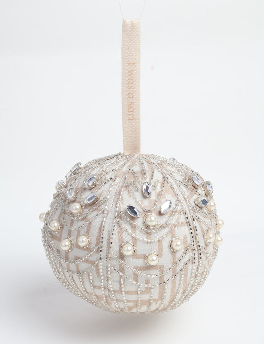 Silver colored ball ornament handcrafted from recycled sari fabric with silver embroidery and beads, representing upcycled clothing, sustainable women’s clothing, green fashion, slow fashion, and eco friendly fashion made from recycled materials.