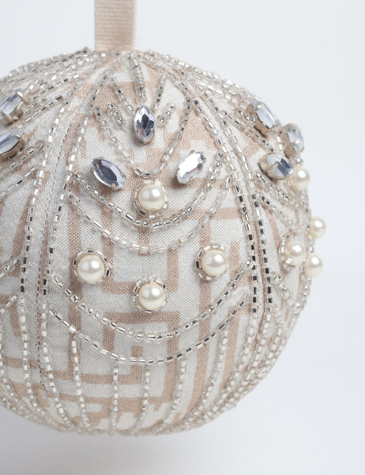 Silver fabric ball ornament with beige geometric pattern, decorated with clear beads, faux pearls, and rhinestones, hanging view