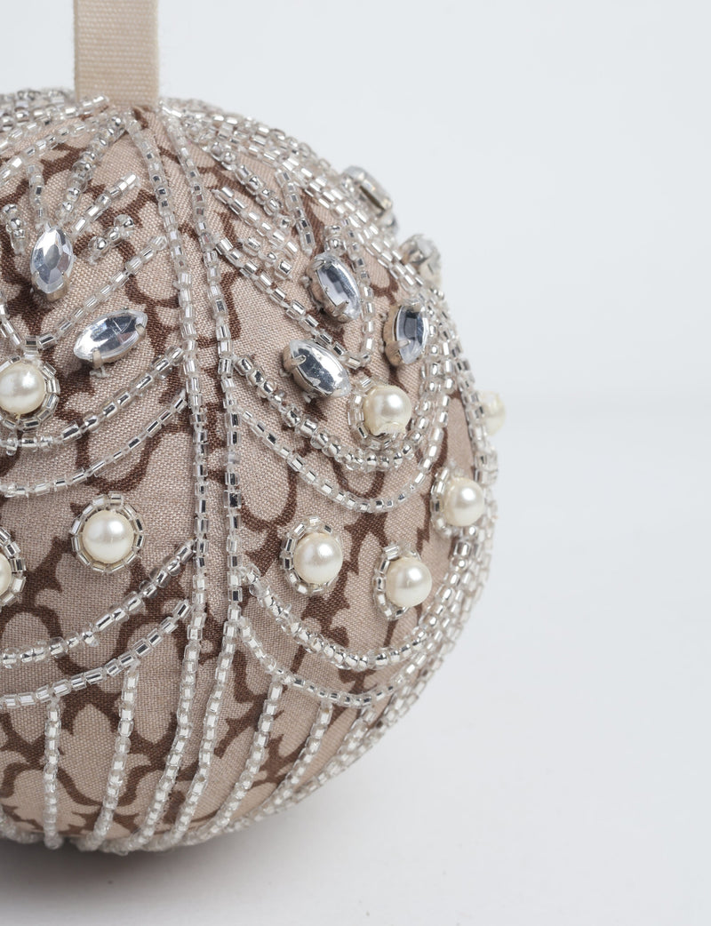 Beige fabric ball ornament with brown pattern, decorated with silver beads, clear gems, and pearl-like accents, hanging by