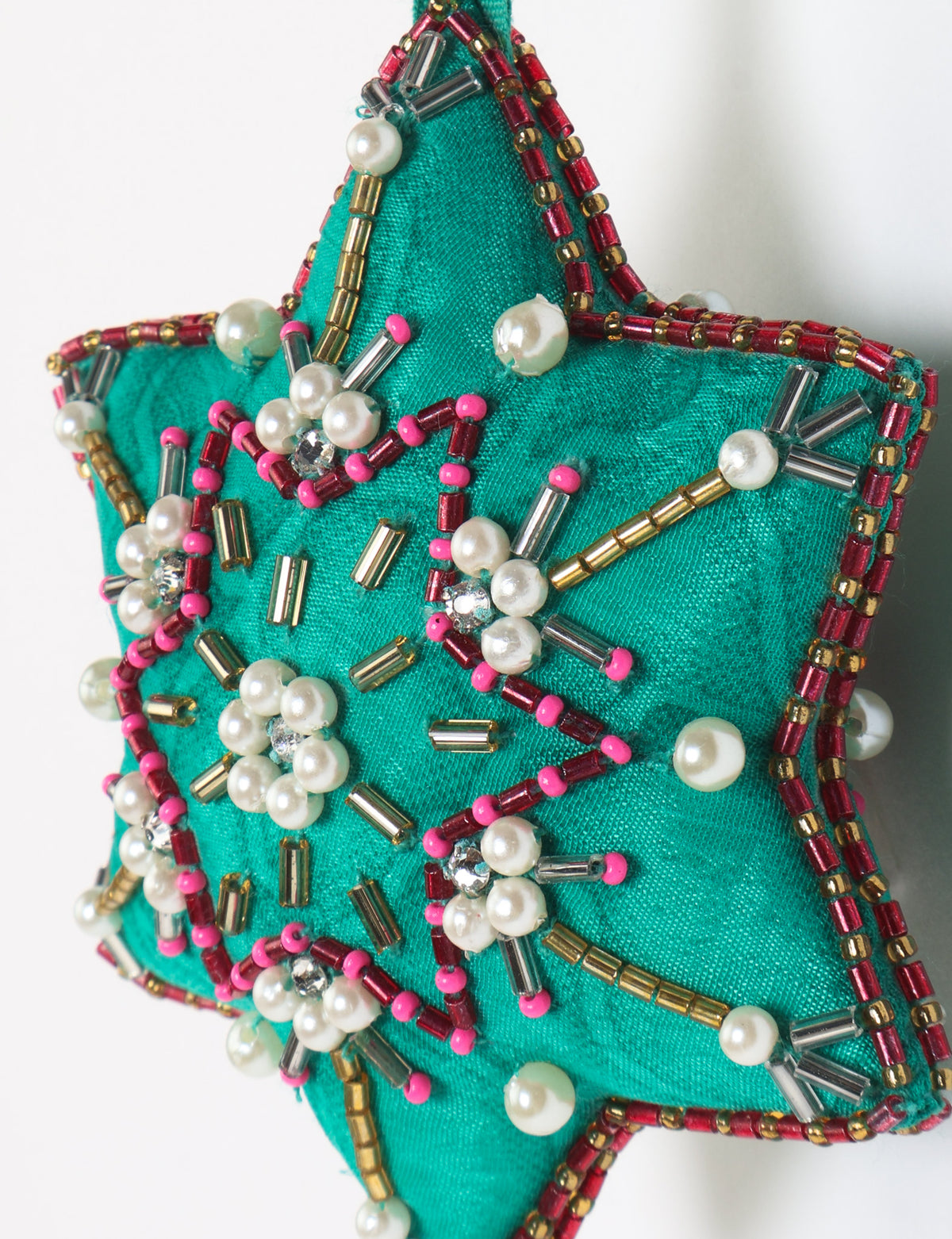 Teal fabric star-shaped snowflake ornament with bead and pearl embellishments, hanging by a teal fabric loop