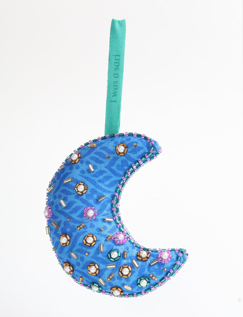 Blue fabric crescent moon ornament with beaded floral and pearl embellishments, hanging by a turquoise loop