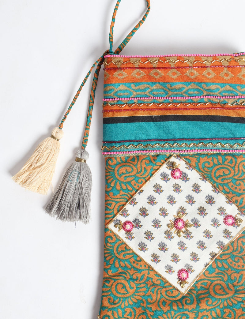 Christmas stocking in blue and orange paisley pattern with decorative tassels and beaded embellishments, flat lay view