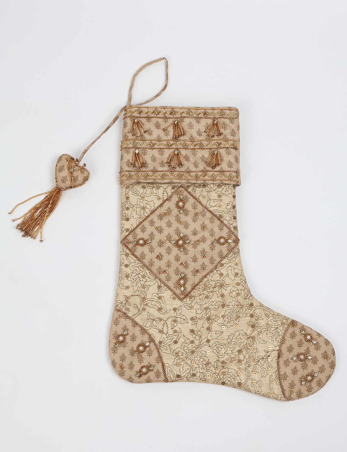 Beige patchwork Christmas stocking with floral patterns, gold bead tassels, and a heart-shaped hanging loop with tassel